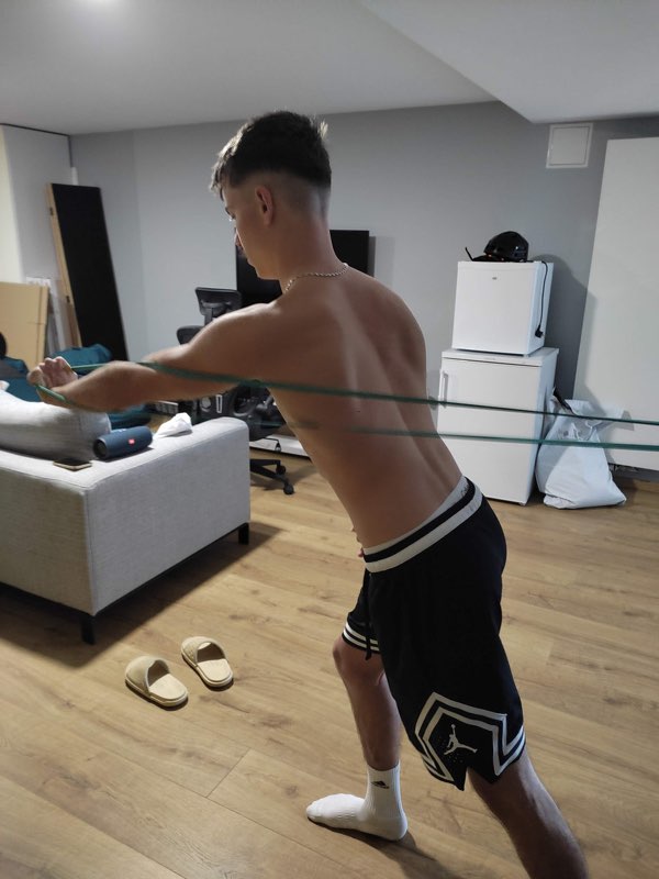Jeune sportif en travail d'épaules à l'élastique, à son domicile
